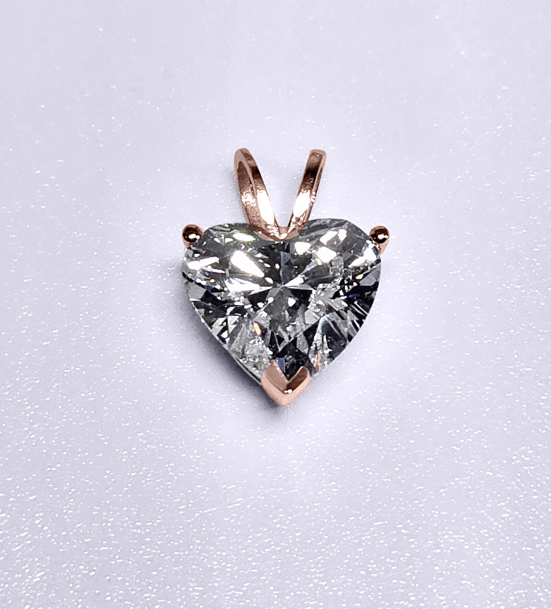 Heart-shaped diamond pendant on a light gray background